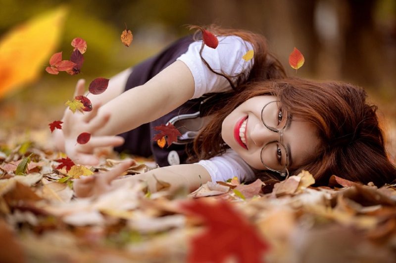 hình gái xinh đeo kính nằm trên lá khô
